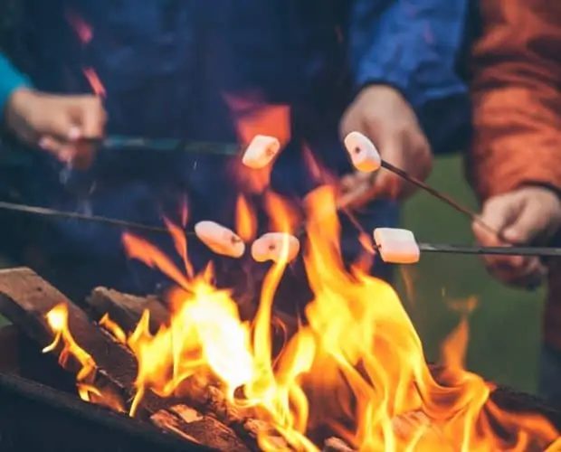 hands of friends roasting marshmallows over the fire