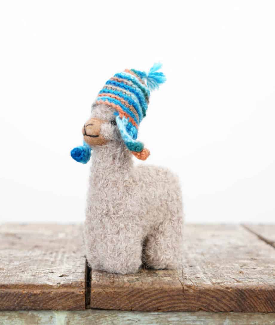 beige baby alpaca toy with a turquoise hat