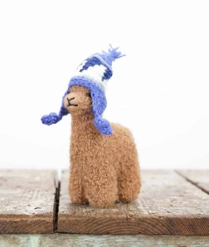 brown baby alpaca soft toy with a blue hat