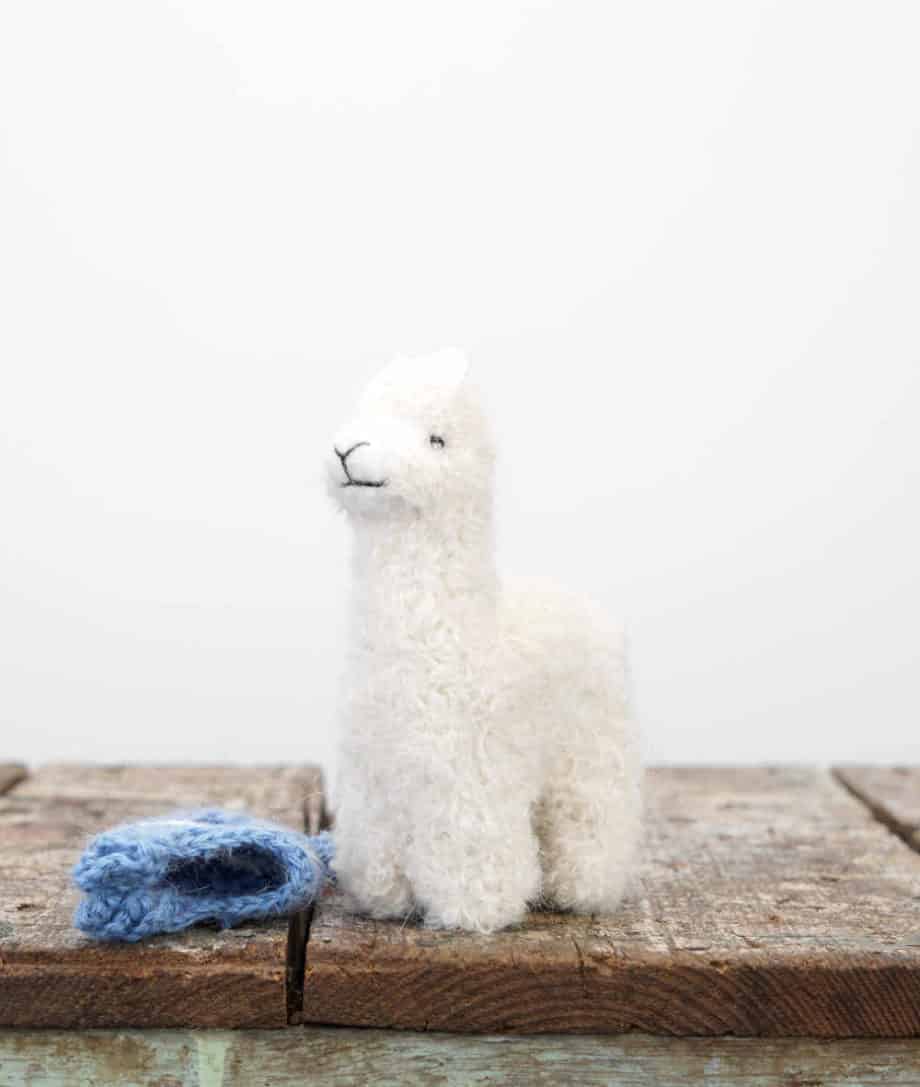 super cute white baby alpaca soft toy with a blue hat