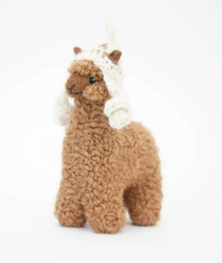 cuddly brown baby alpaca with a cream hat